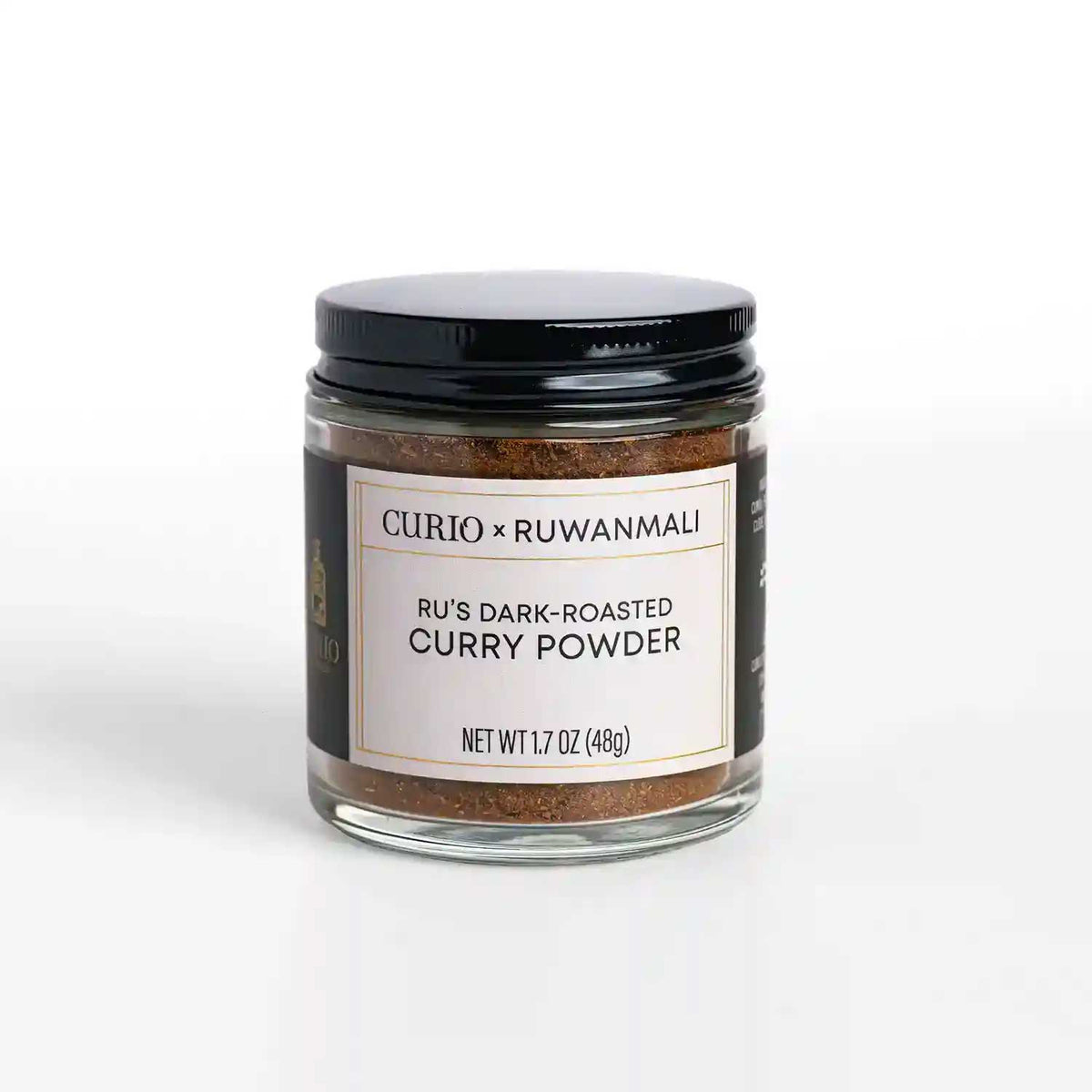 A glass jar of Ru's Dark-roasted Curry Powder, a collaboration blend with Curio Spice and Ruwan Samarakoon